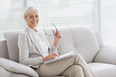 portrait of happy therapist with notes sitting on sofa in office